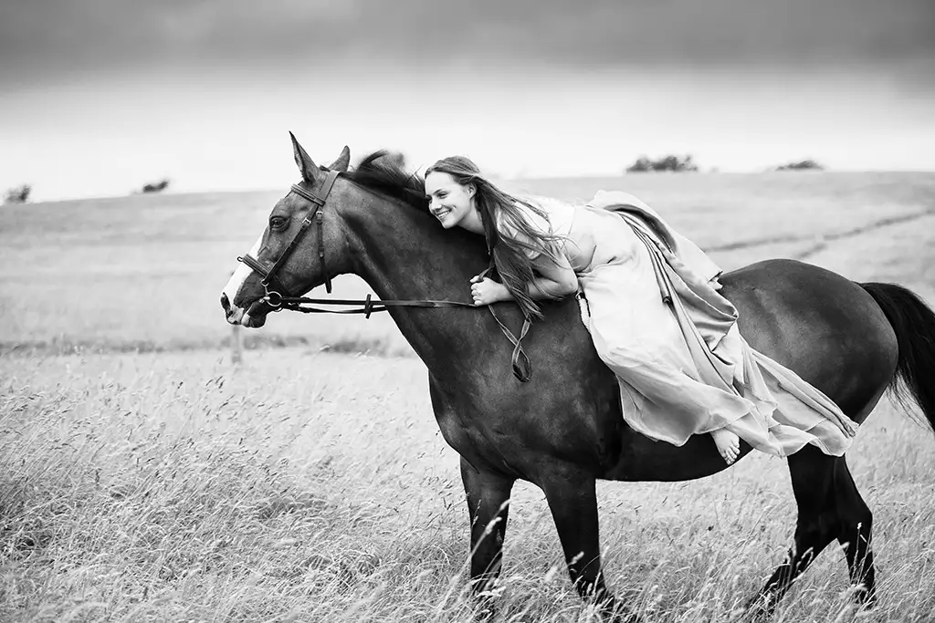 black and white photo of girl riding horse